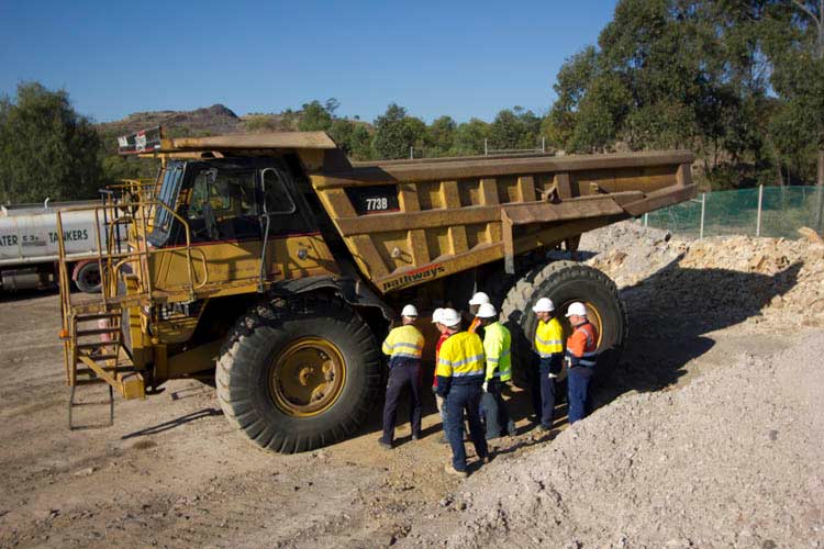 dump truck course training group of students standing round haul truck high vis outfits iMINCO