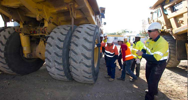 Mining training haul truck course students on site inspecting rear tyres